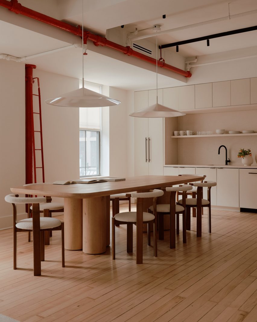 A large wooden dining table and several chairs in front of a kitchen