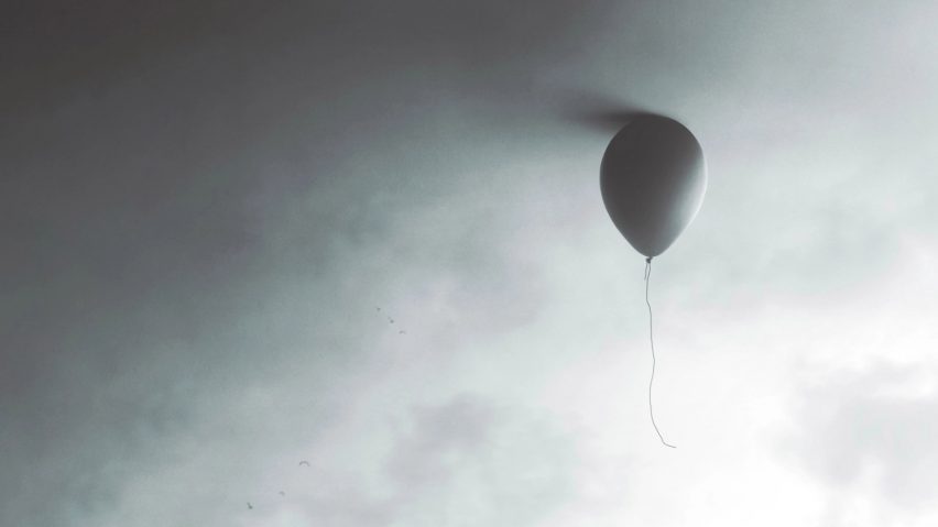 Grey balloon floating in front of grey background