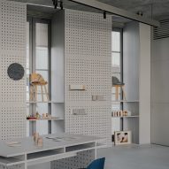 Perforated metal panels with items on display alongside chair and desk