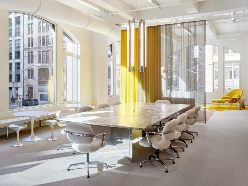 Large conference table in front of a yellow and metal mesh curtains