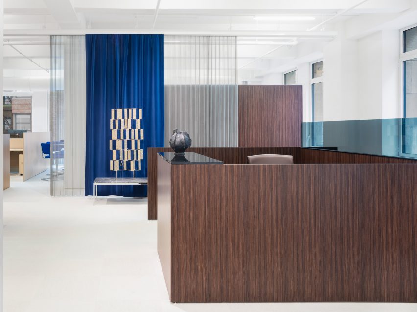 Sculpture in front of a blue curtain with a dark wood partition in the foreground