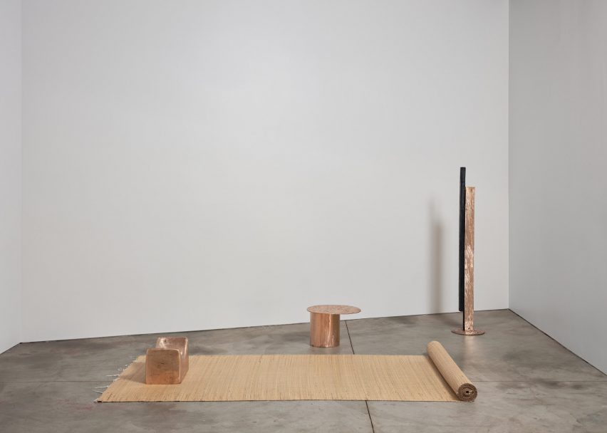 Photo of three copper objects laid out within a bare gallery space