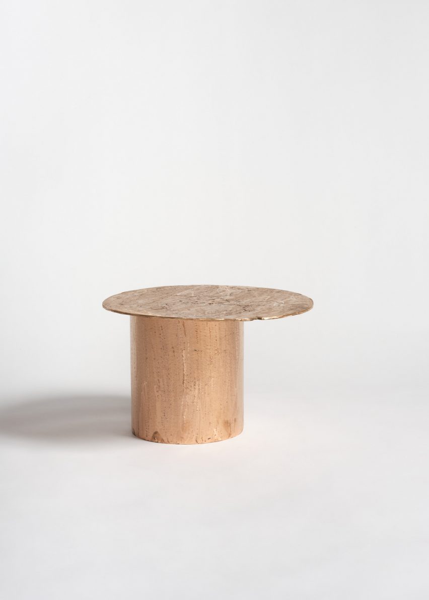 Photo of a small copper side table consisting of a flat disc-shaped top and a chunky cylindrical base