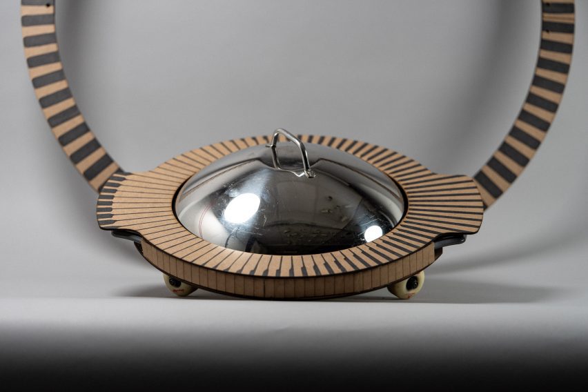 Photo of a circular cardboard object with a metal lid and skateboard wheels created by students Emily Straughn, Paul Goss and Kelly Chen