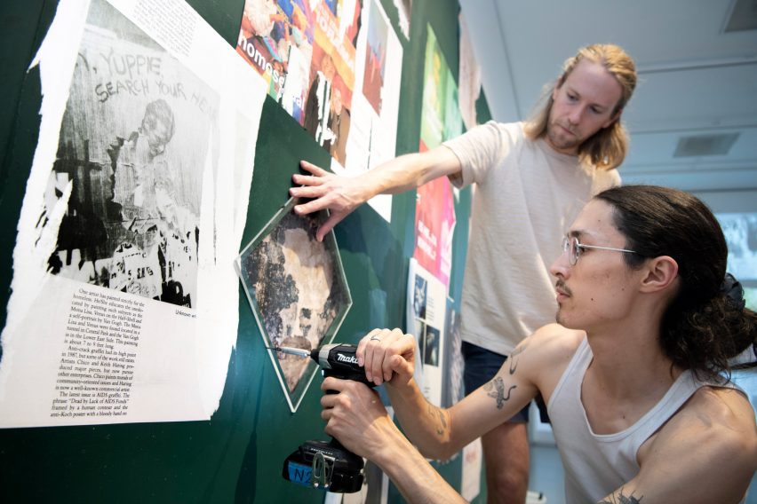A photograph of two people adding to a noticeboard.