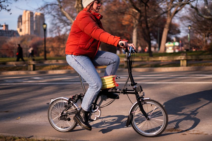 A photograph of a person riding a bike on grey pavement.