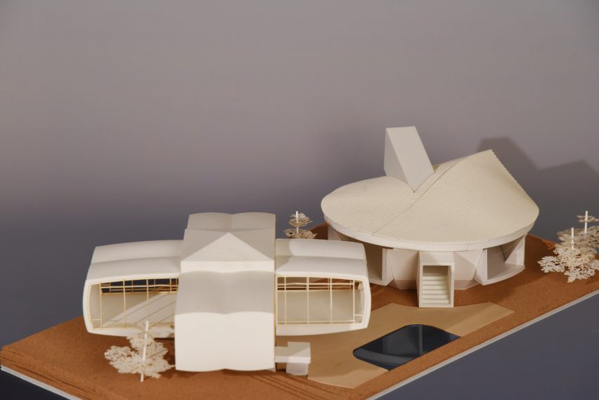 A photograph of a white architectural model atop a brown surface.