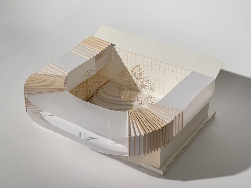 A photograph of an architectural model in tones of beige and white, against a white backdrop.