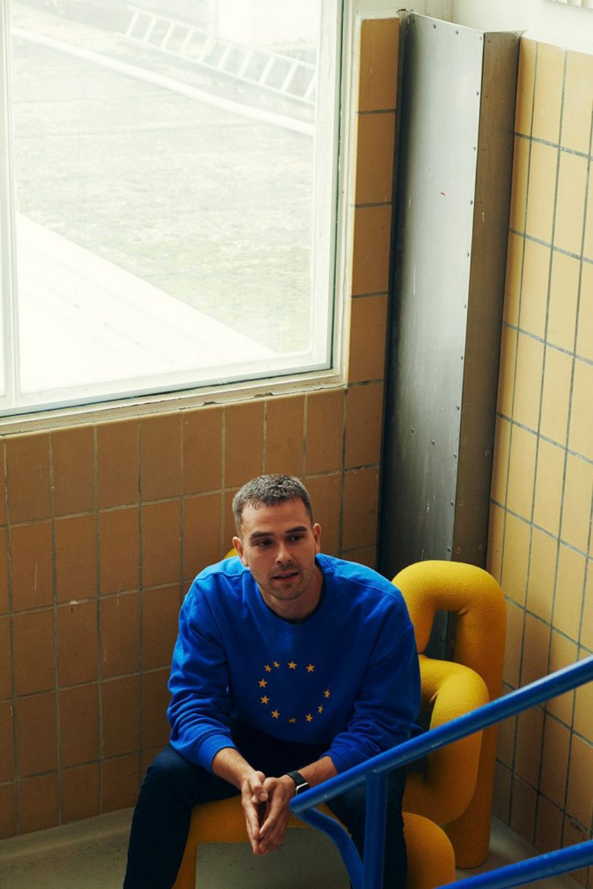 Photo of Kaave Pour wearing a blue EU jumper and sitting in a stairwell