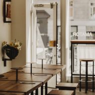 Photograph of the communal table area facing the large glass facade.