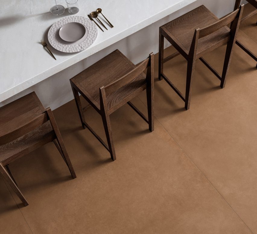 a photograph from above of a brown tiled floor with brown wooden chairs and a white table on it