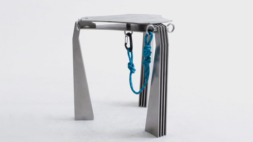 A photograph of a silver stool with a blue rope attached to it, which hangs underneath it