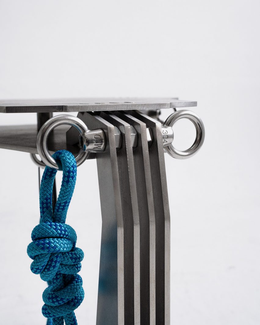 A close up photograph of a silver metal stool, with a blue rope tied to it