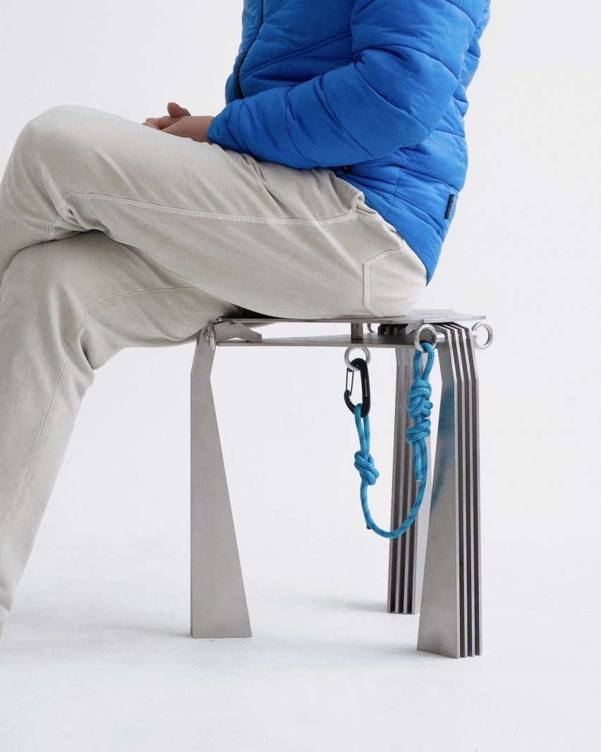 A photograph of a person sat on a silver stool
