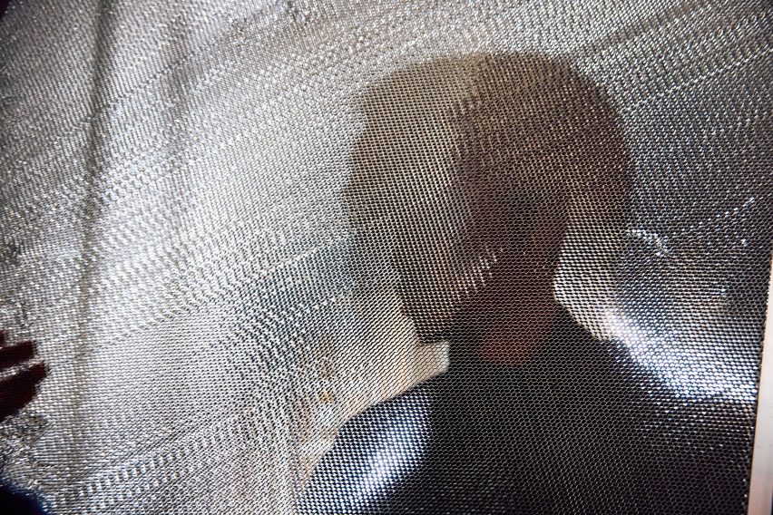 Close up of aluminium honeycomb material with silhouette of figure standing behind it