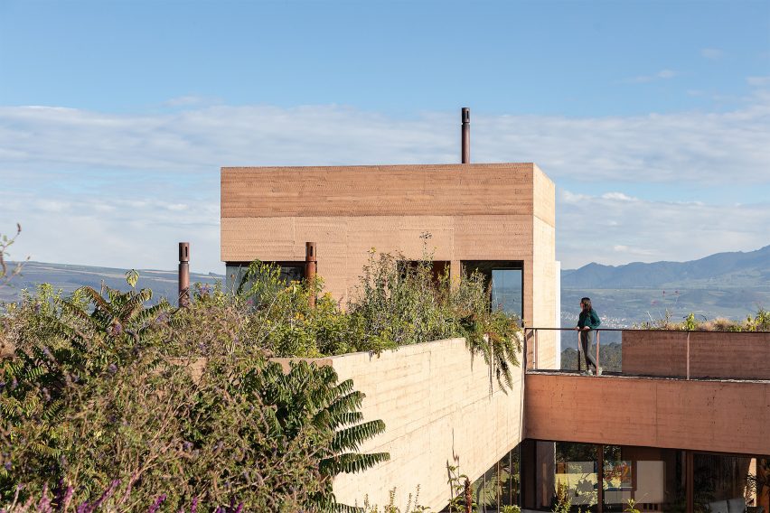 Board-formed concrete tower with greenery and person standing on elevated walkway