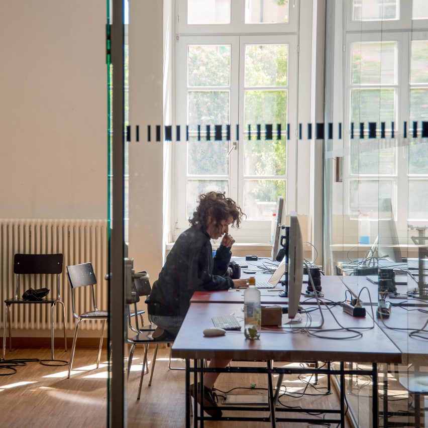 A photograph of a person sat at a desk using a computer.
