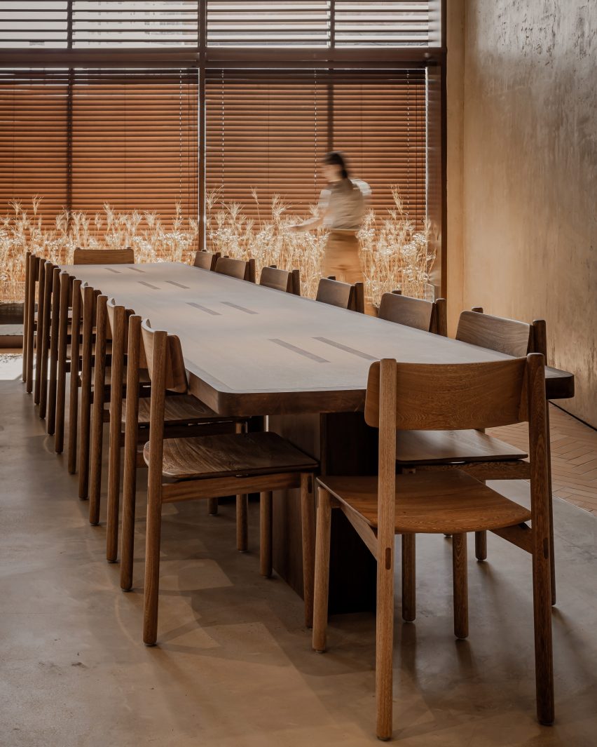 A large communal wood table with wheat in the background