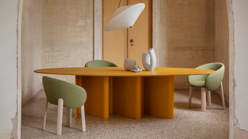 A photograph of an orange table with green chairs around it.