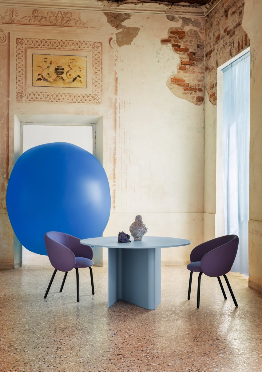 A photograph of a blue table with purple chairs around it, and a large blue balloon behind it