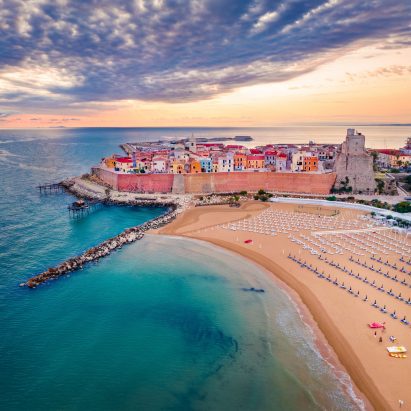 A photograph of a beach next to a town with red buildings