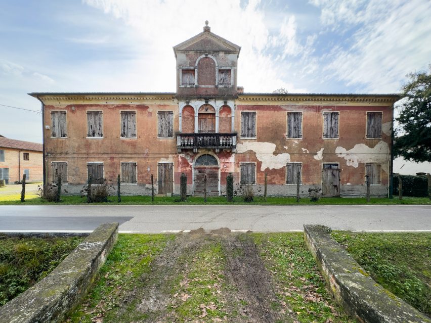 A photograph of a large abandoned stone building in tones of brown and grey.