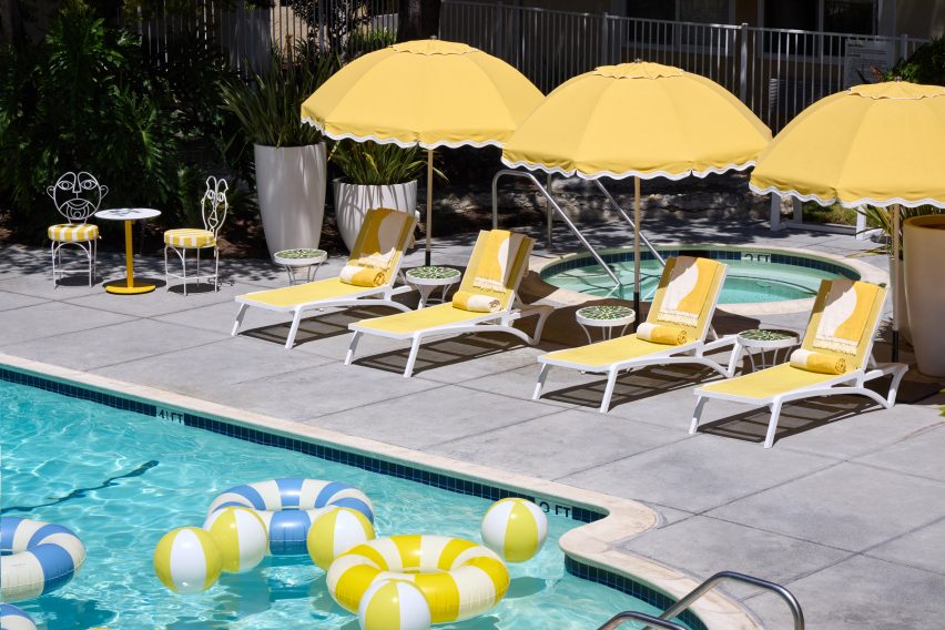 A pool terrace with yellow loungers and parasols lined up along the water side