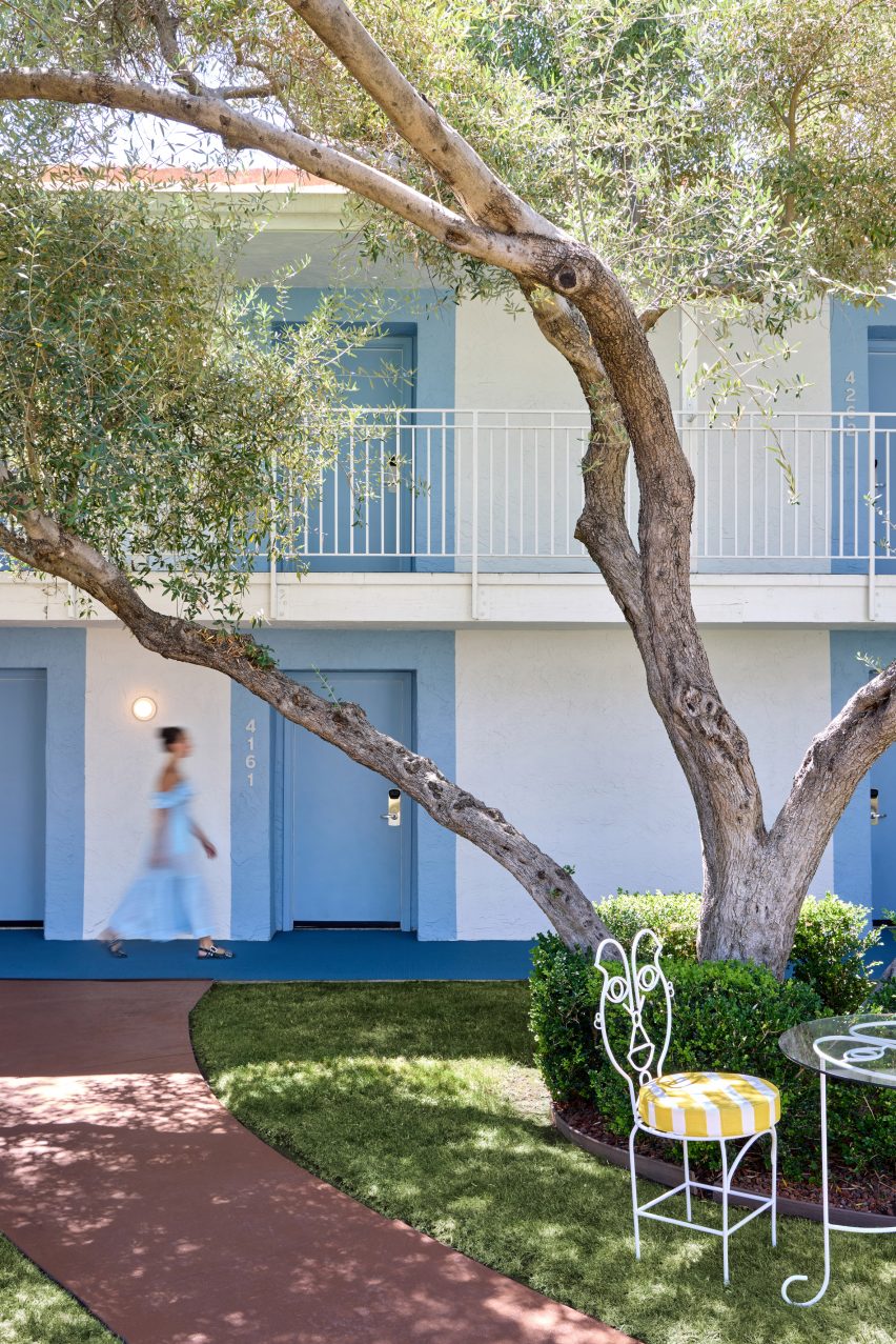 Outdoor view of a two-level hotel with sky blue room doors