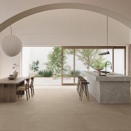 A photograph of a kitchen with grey and brown furniture in it, white walls and a beige-tiled floor