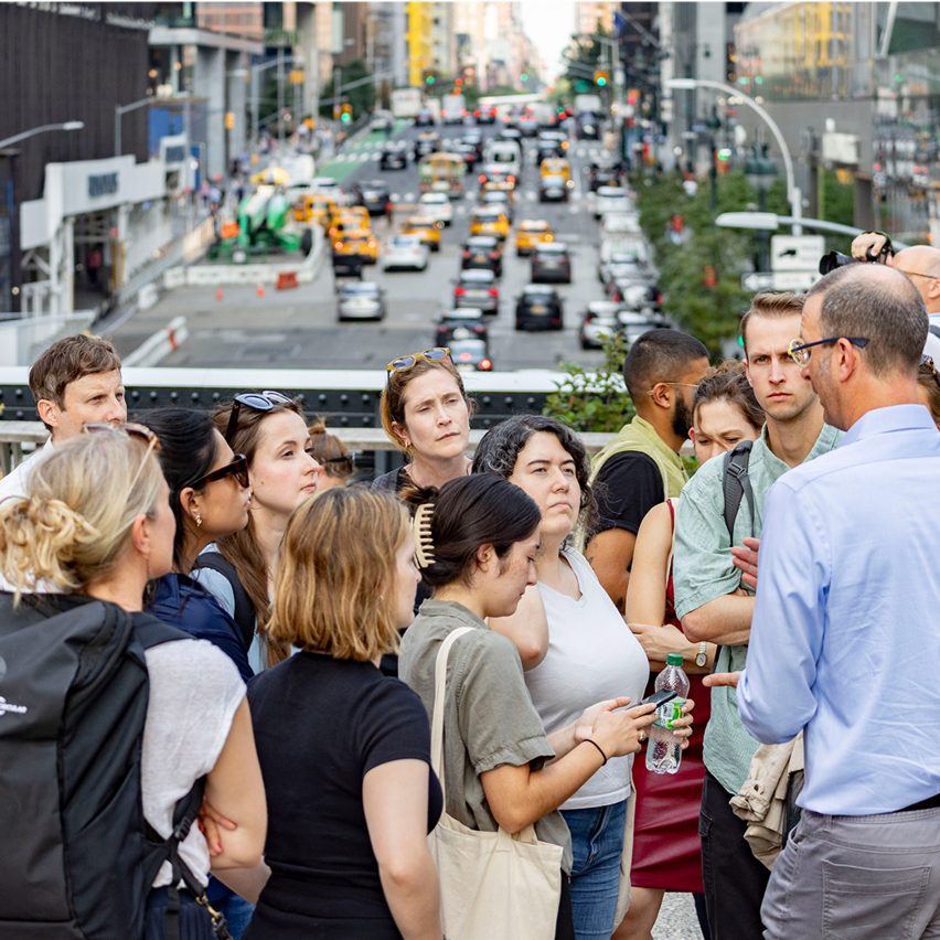 a photograph of a group of people by a busy road with traffic.