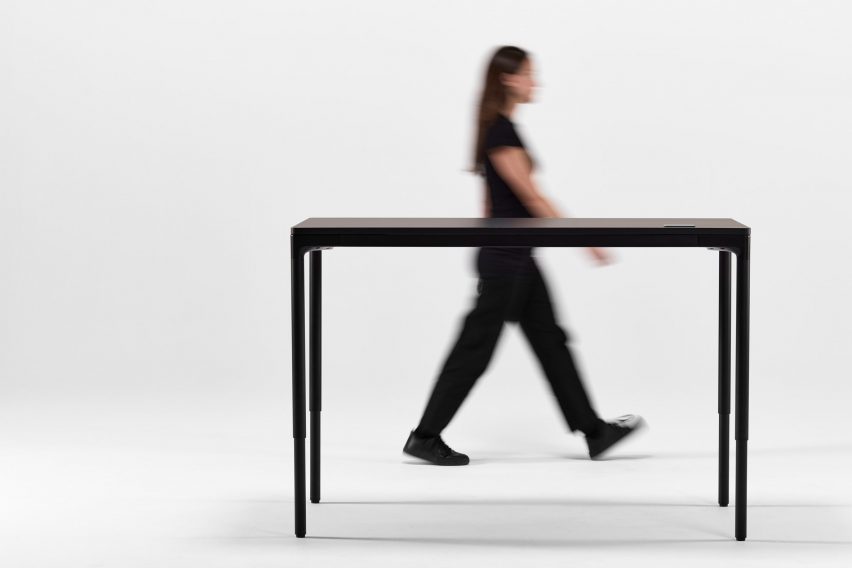 Person walking past black eFloat Quattro desk