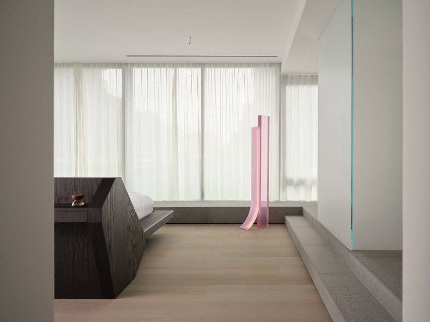 Minimalist primary bedroom featuring a custom bed and a pink floor lamp