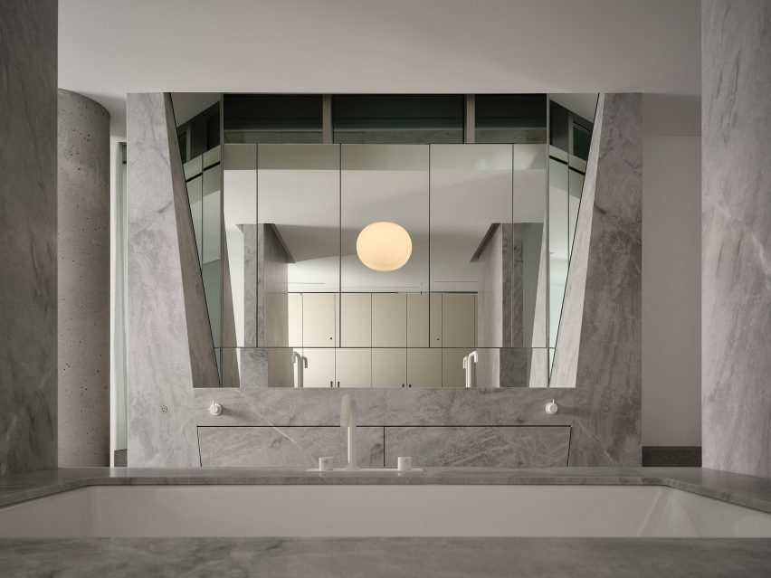 Pale-gray marble and faceted mirrors line a bathroom