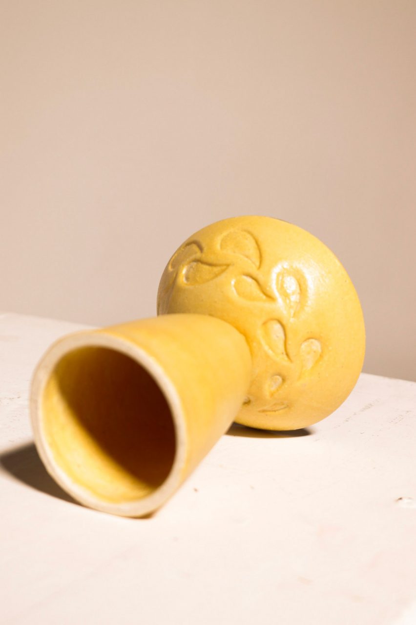 a photograph of a yellow ceramic vase leant over on its side