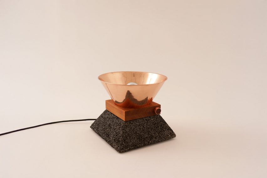 a photograph of a lamp in tones of copper and brown against a beige backdrop