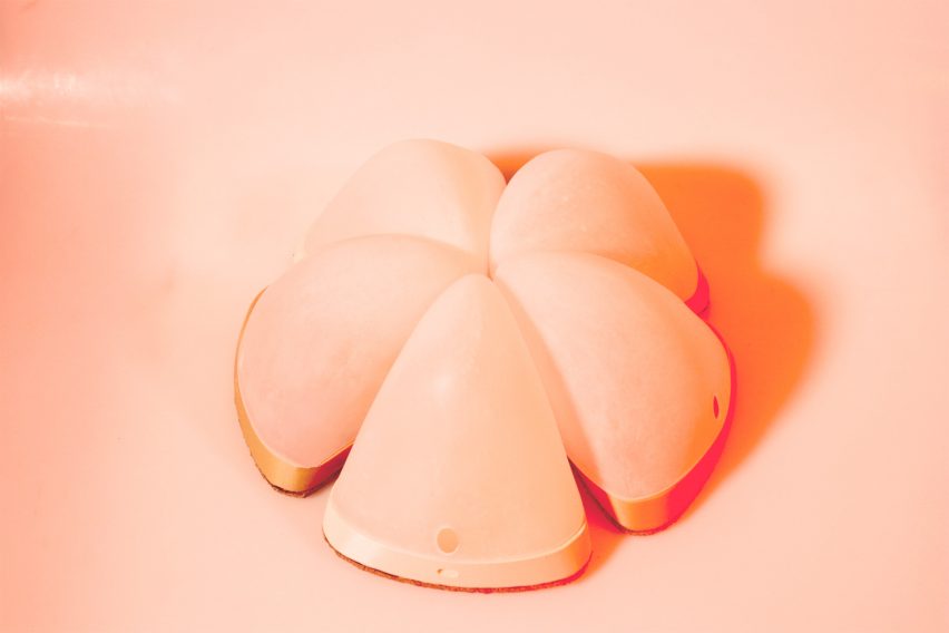 a photograph of a lamp in tones of orange and pink, shaped in a circular form and split into segments 