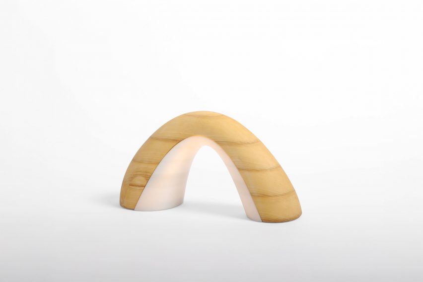 a photograph of a lamp, in the shape of an arch, in tones of beige and white against a white backdrop