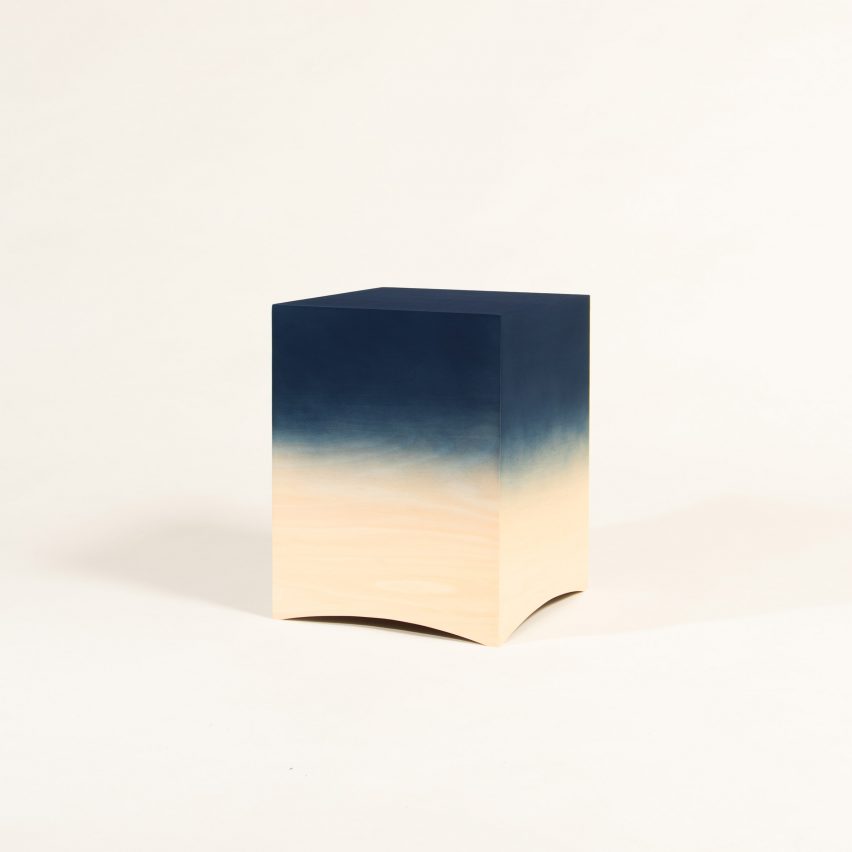 a photograph of a wooden stool in the shape of a cube and in tones of blue and beige