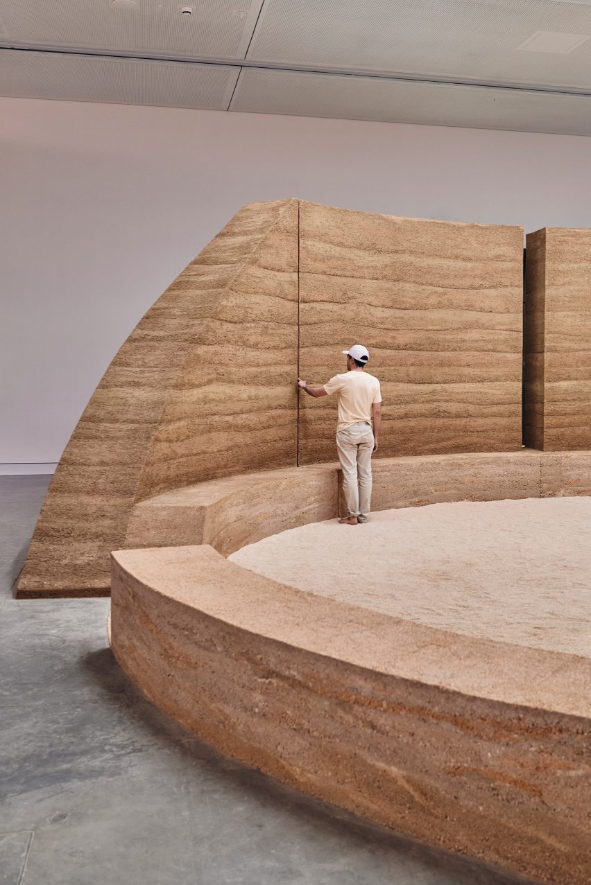 Photo of a rammed earth wall and ring of bench seating with sand in the middle forming a ceremonial ground in the Australia pavilion at the Venice Architecture Biennale 2025