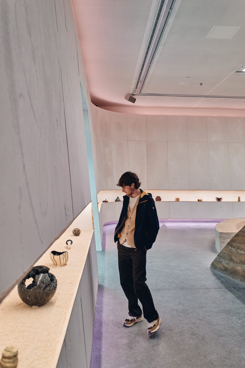 Photo of a person looking at sculptural objects arranged along a linear display shelf within the Australian pavilion of the Venice Architecture Biennale 2025