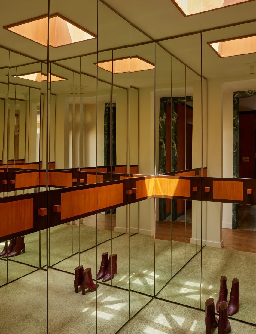 Closet is wrapped in mirrors, interrupted by a horizontal band of two-toned wood