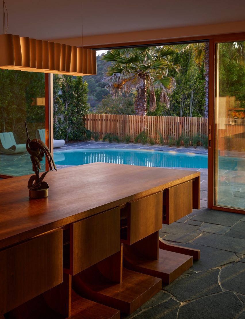 Black flagstones extend through sliding glass doors to a lush back yard