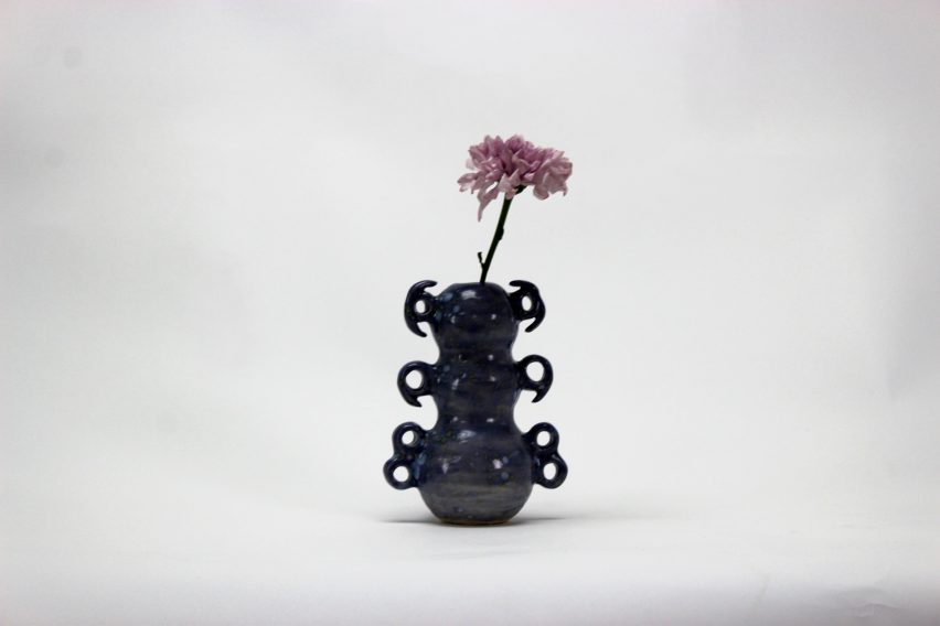 a photograph of a blue abstract-shaped vase with a flower in it