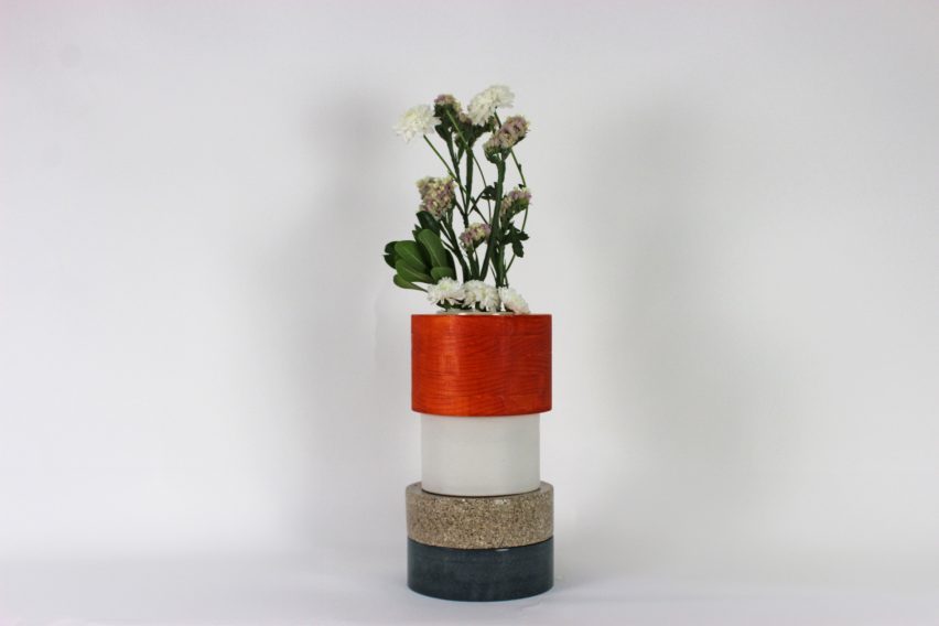a photograph of a vase in tones of red, white, beige and black, holding flowers
