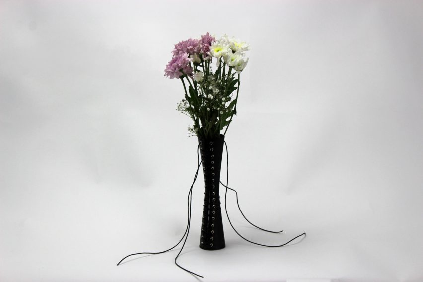 a photograph of a black lace up vase with flowers in it