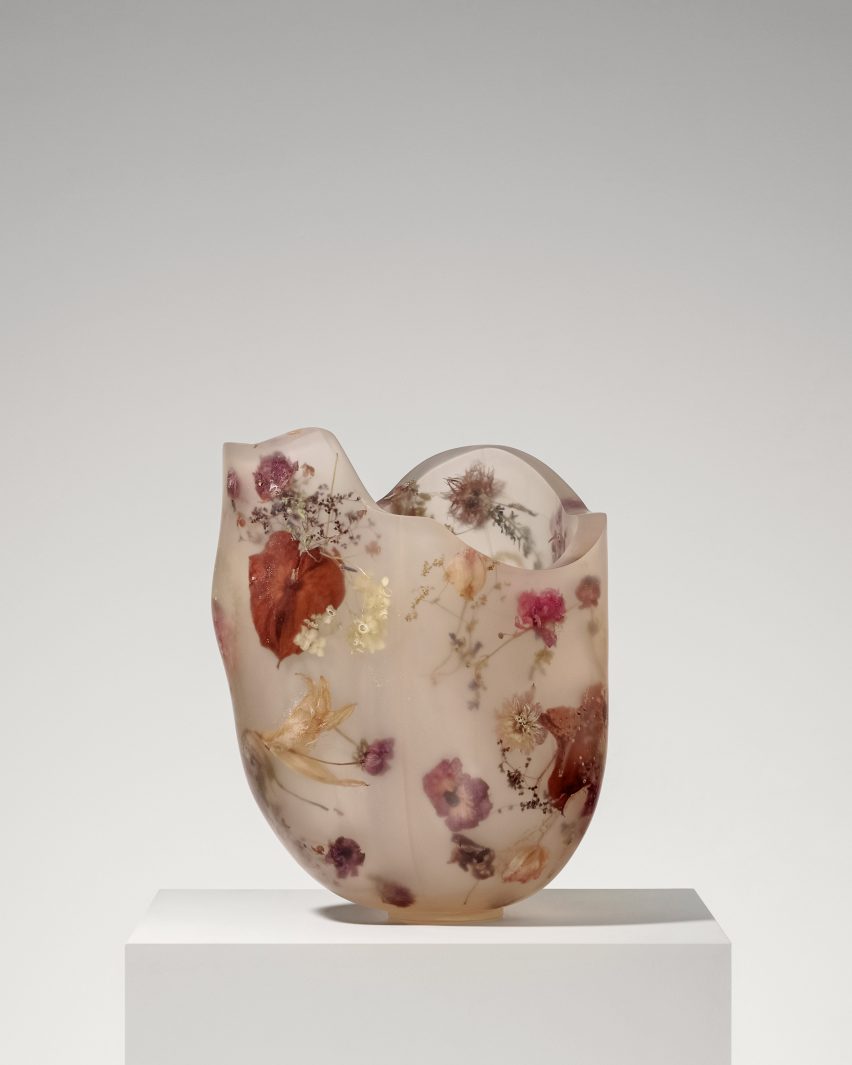 A vessel made from resin and flowers on top of a white pedestal