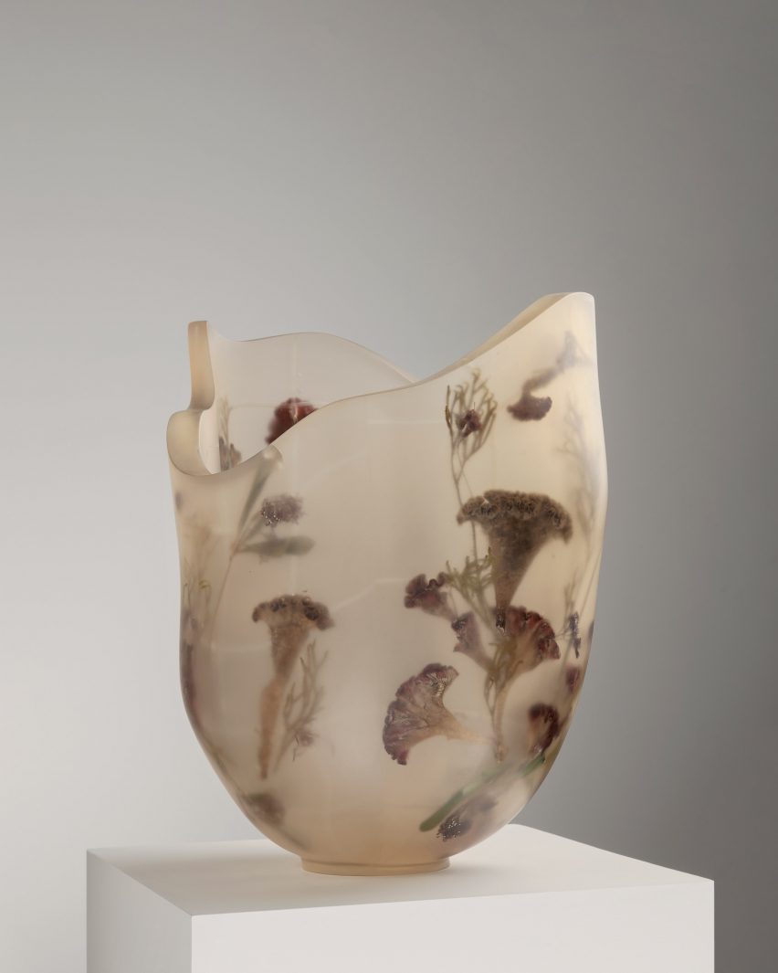 A vessel made from resin and flowers on top of a white pedestal
