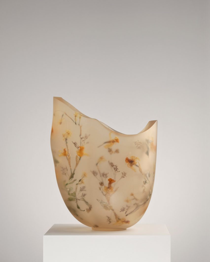 A vessel made from resin and flowers on top of a white pedestal