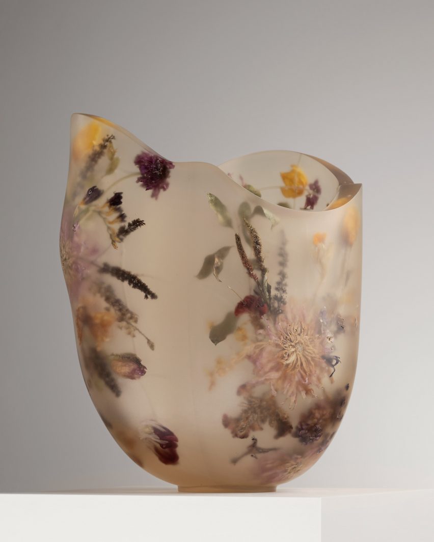 A vessel made from resin and flowers on top of a white pedestal
