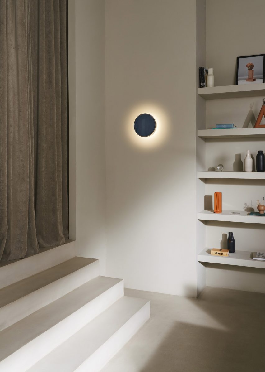 a photograph of a blue circular wall light beside a bookshelf and staircase